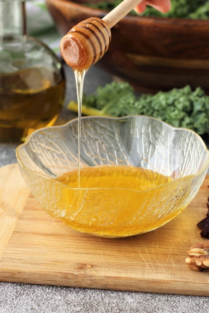 pouring honey in glass bowl with vinaigrette
