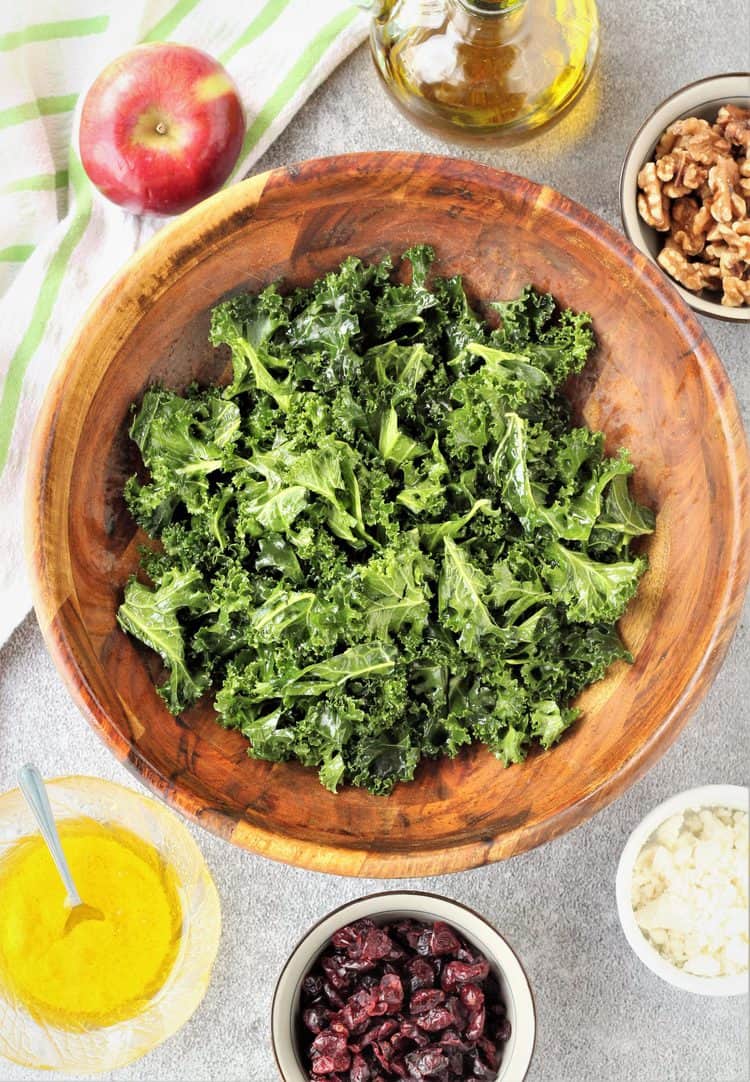 kale leaves in salad bowl with bowls with other ingredients around it