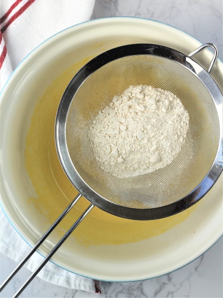 sifted flour over bowl with egg yolks