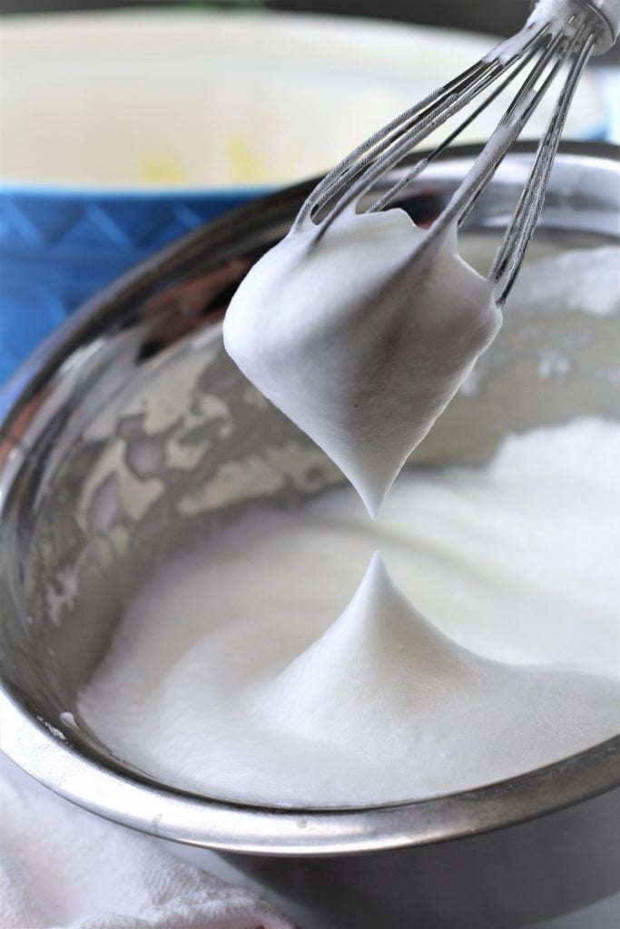 whisked egg whites on whisk over metal bowl