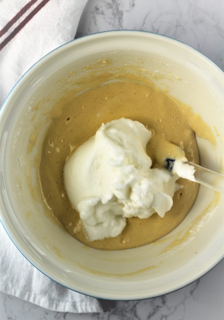 adding egg whites to bowl with eggs with spatula