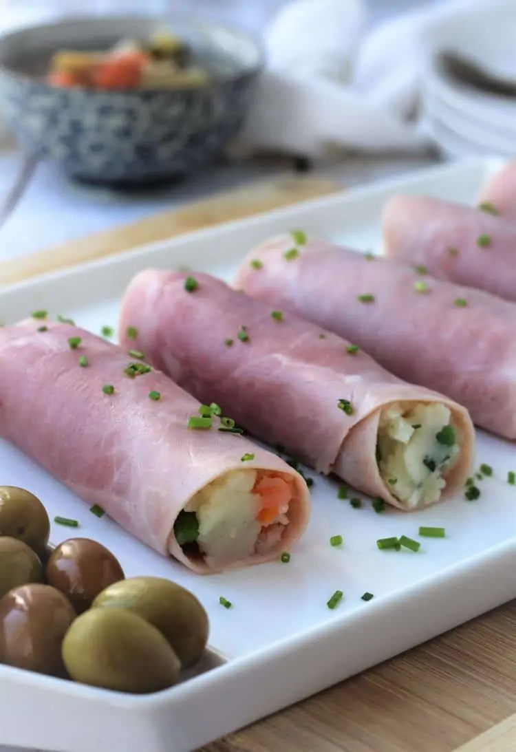 prosciutto cotto rolled with russian salad on white platter