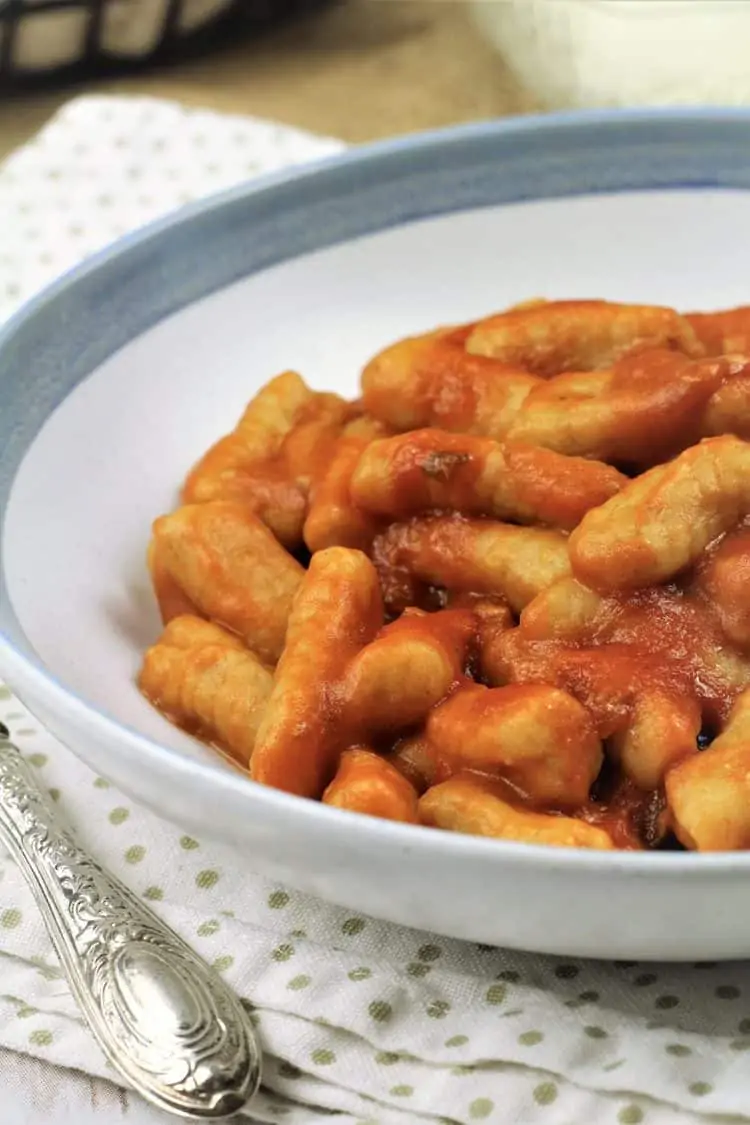bowl of gnocchi with tomato sauce on poka doted napkin
