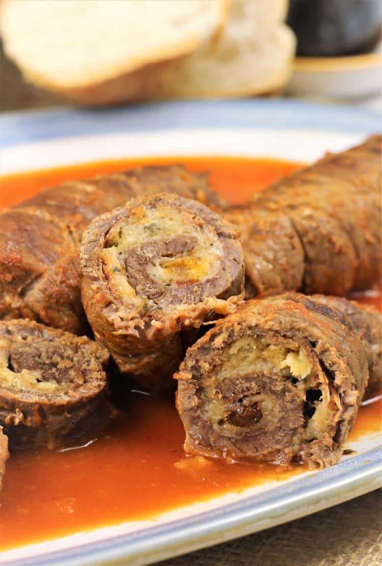 beef braciole cut in half on platter with tomato sauce 