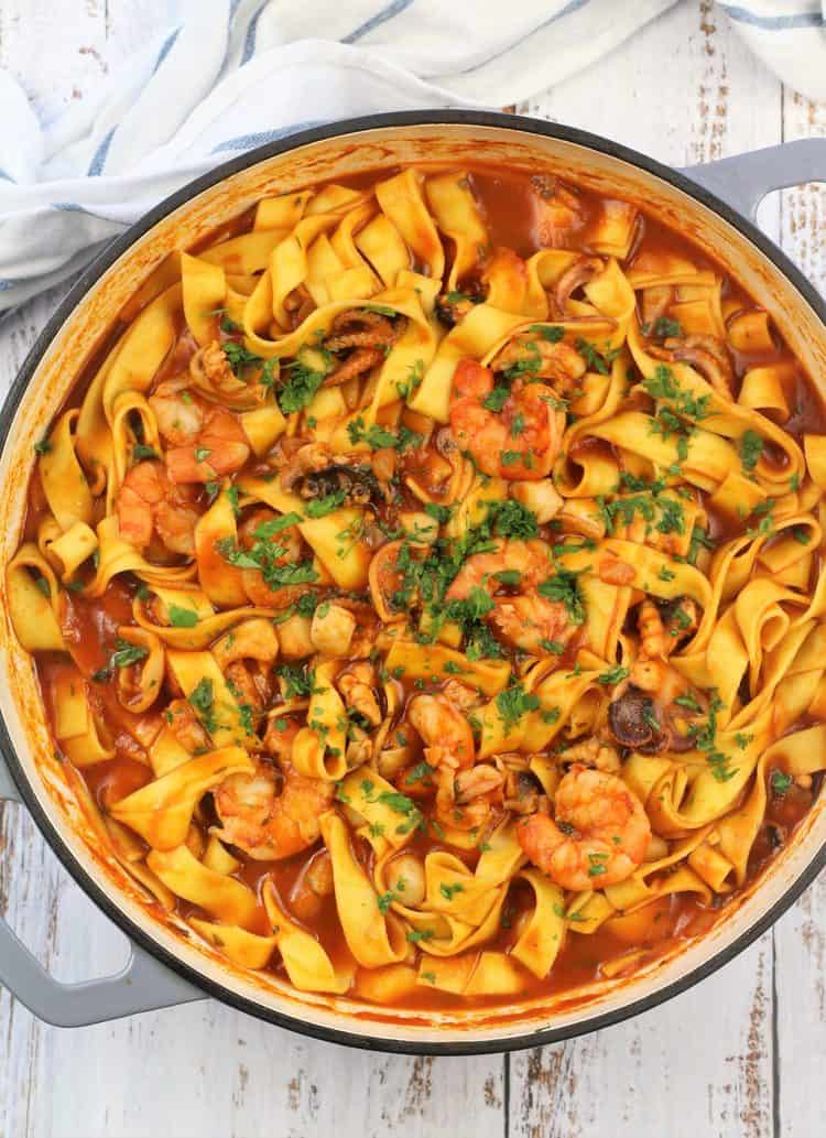 large grey skillet filled with pasta and tomato seafood sauce