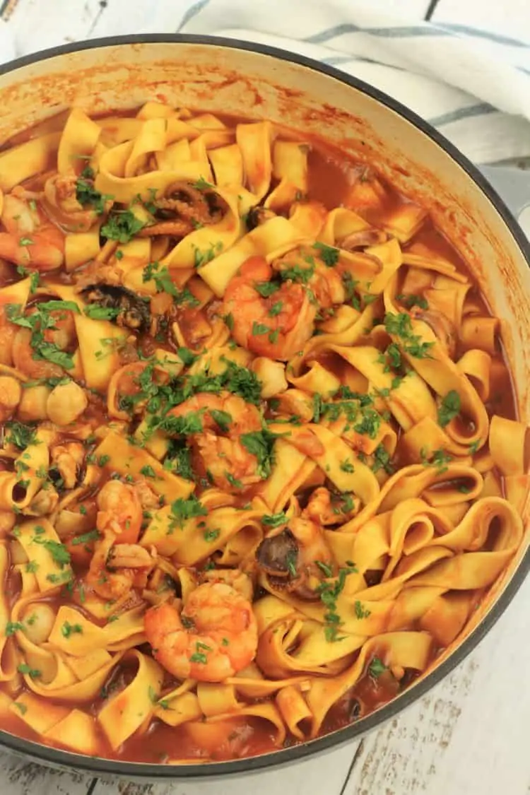 large grey skillet filled with pasta in tomato seafood sauce
