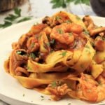 seafood pasta with tomato sauce piled onto a white plate