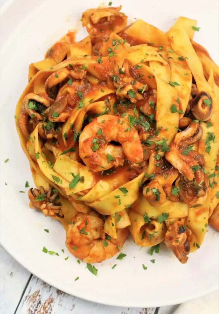 tagliatelle pasta with tomato seafood sauce on white plate