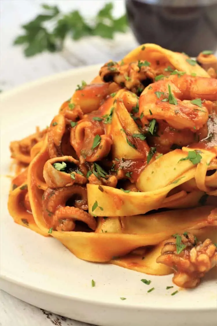 tagliatelle with seafood tomato sauce piled onto white plate 