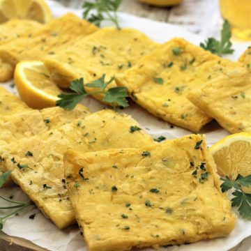 panelle squares on parchment covered board with parsley sprigs and lemon wedges