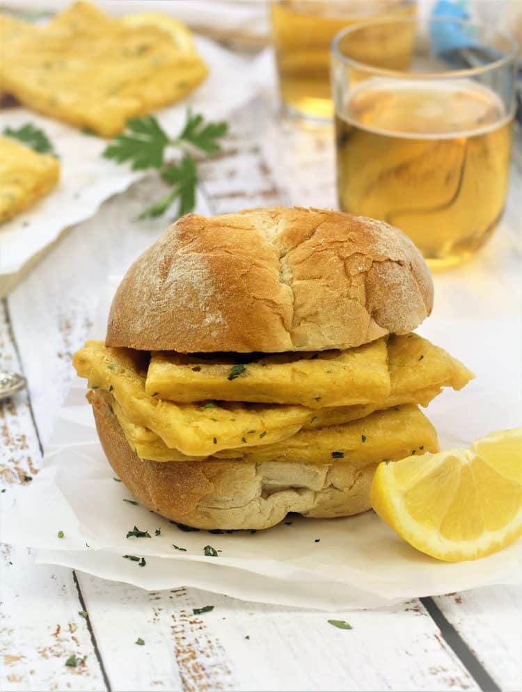 fried panelle in a crusty bun with lemon wedge on side and beer glass in background