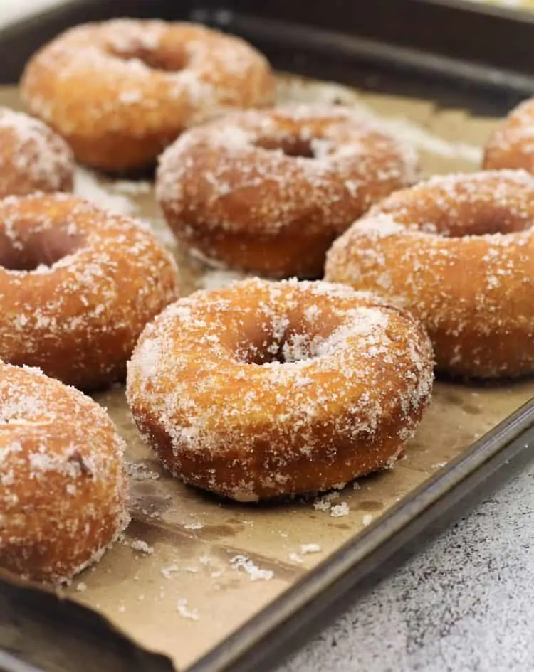 sugar coated doughnuts on brown paper bag on baking sheet 