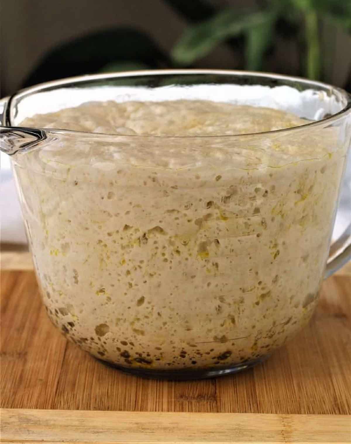 No knead pizza dough in glass measuring bowl.