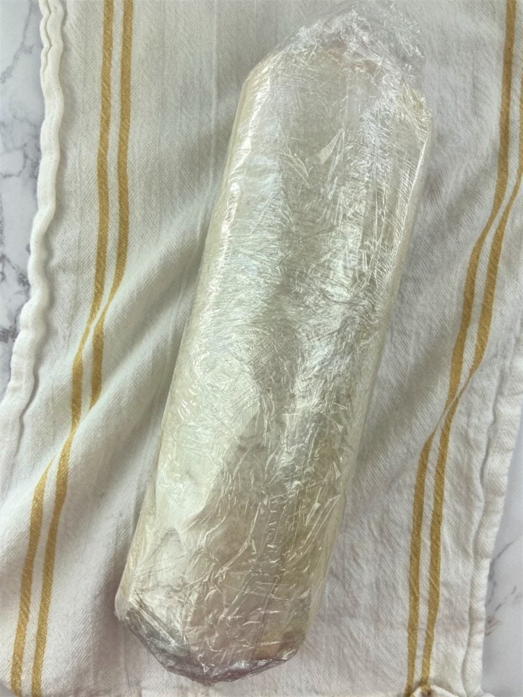 ice cream cake roll wrapped in parchment and plastic wrap