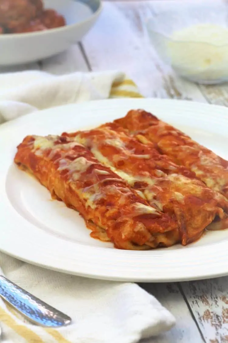 plate filled with crepe cannelloni topped with tomato sauce and mozzarella 