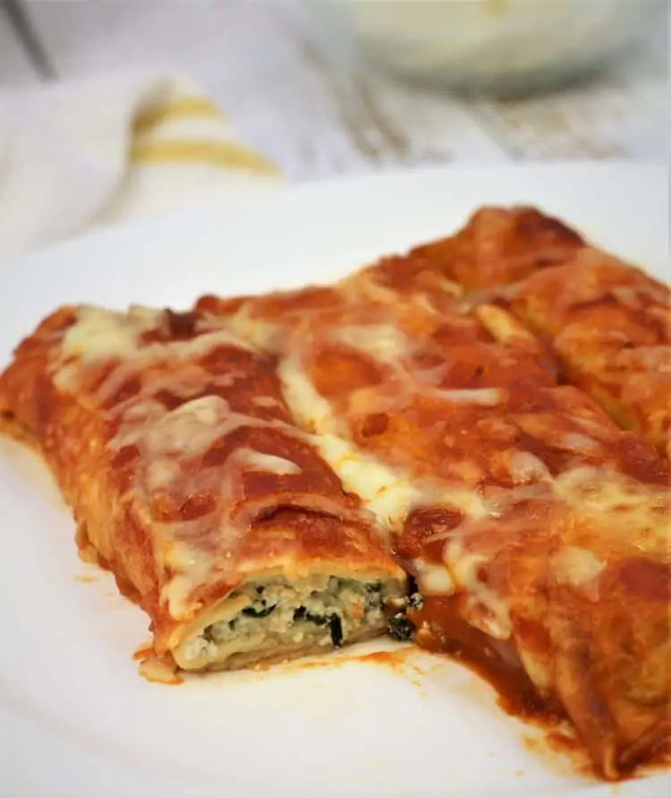 crepe cannelloni with tomato sauce filled with spinach and ricotta on plate 