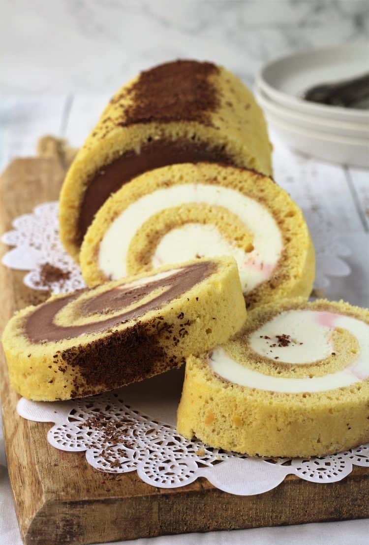 slices of ice cream cake roll on wood board with grated chocolate