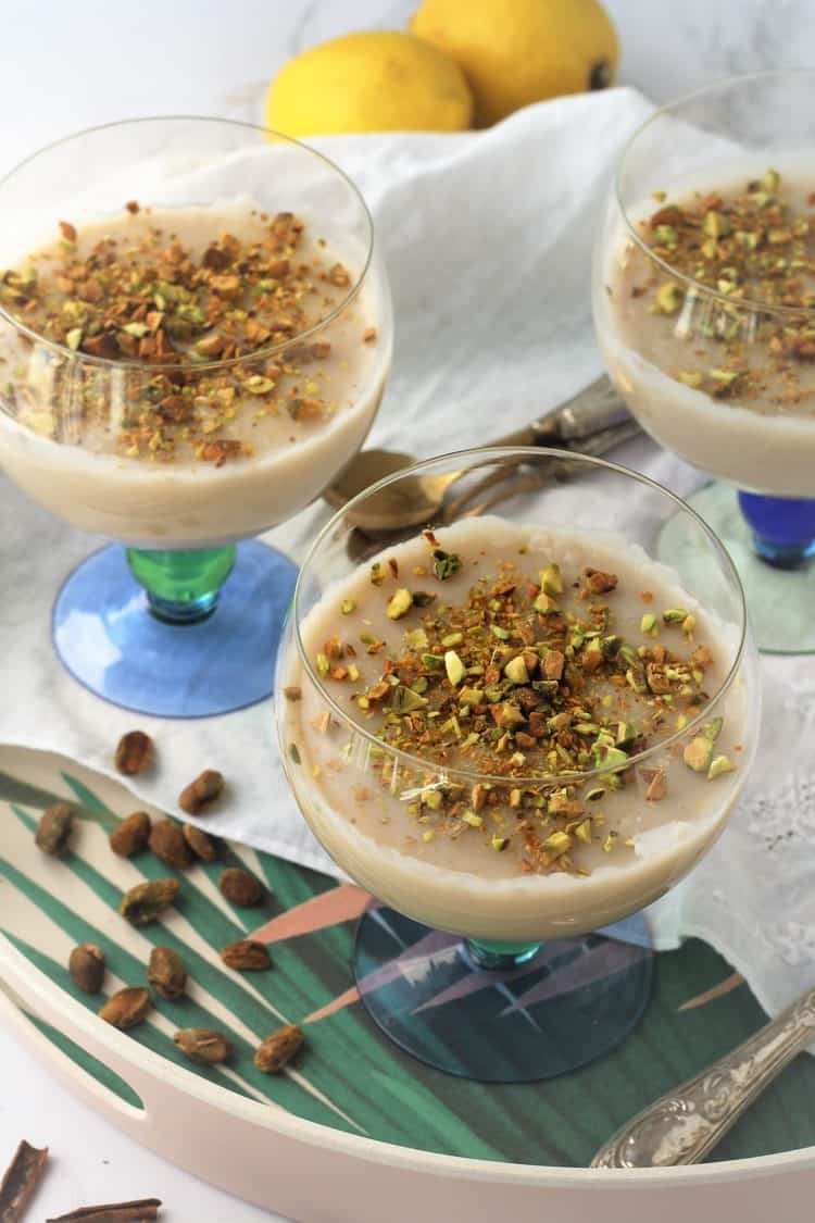 3 glasses filled with almond milk pudding topped with chopped pistachios
