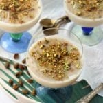 three glasses filled with almond milk pudding topped with pistachios