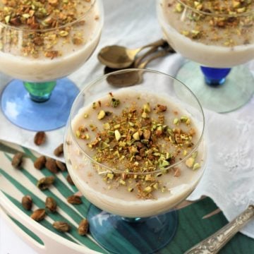 three glasses filled with almond milk pudding topped with pistachios