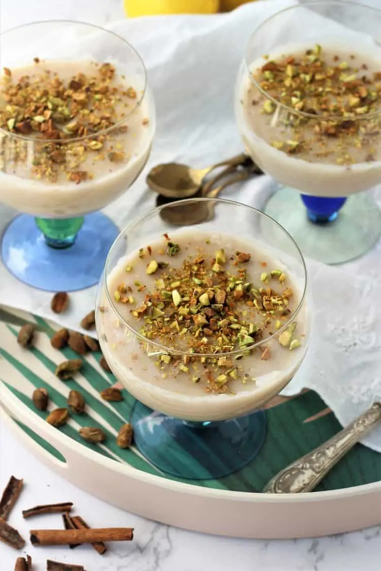 three glasses filled with almond milk pudding topped with chopped pistachios