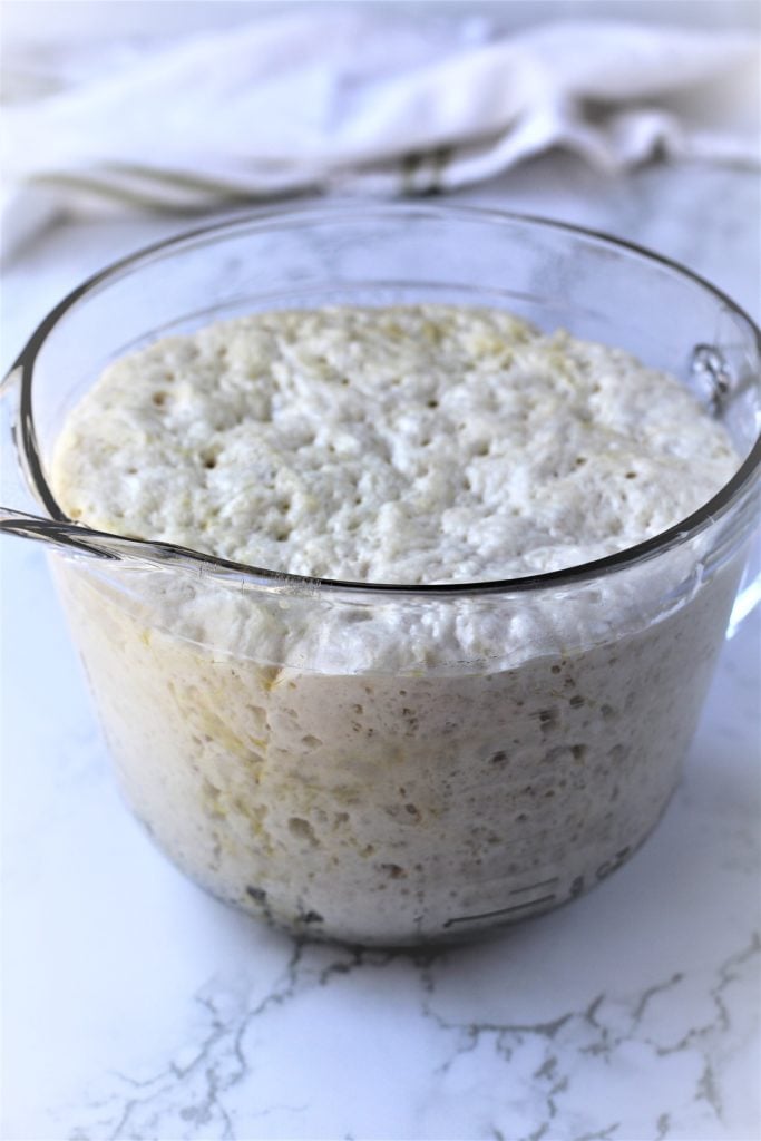 large measuring cup filled with risen pizza dough