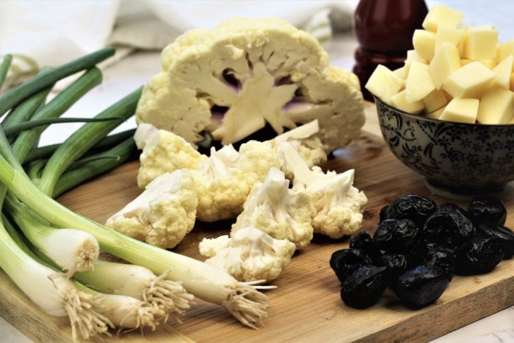 cauliflower, green onions, black olives and cubed cheese on wood board