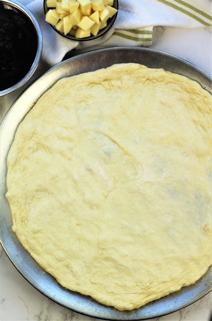 flattened round pizza dough on round pan