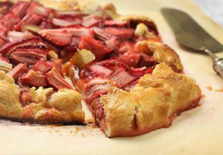 rhubarb strawberry crostata on parchment paper with one slice cut 