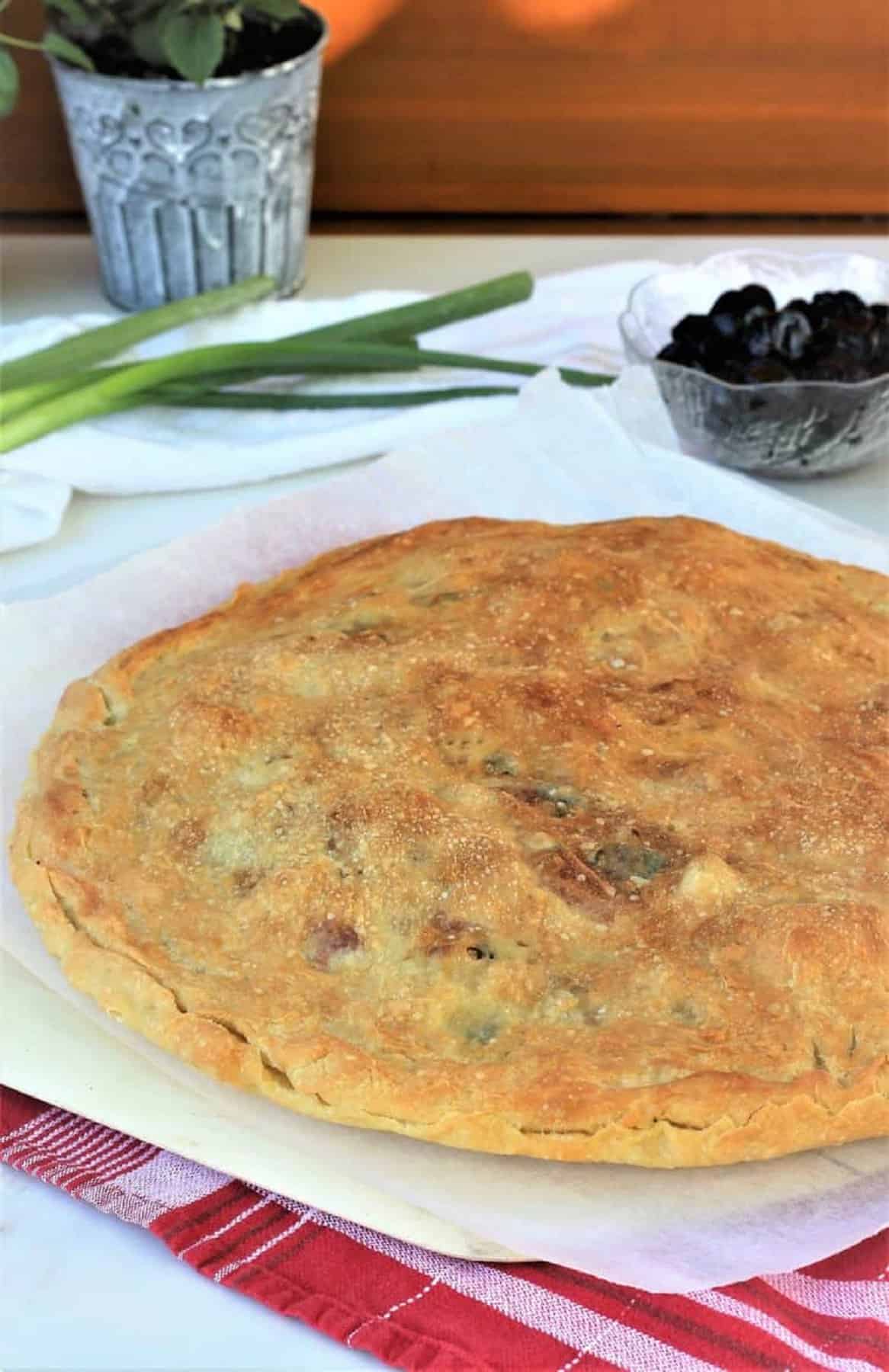 Just baked scacciata filled with cauliflower and black olives on pizza peel.