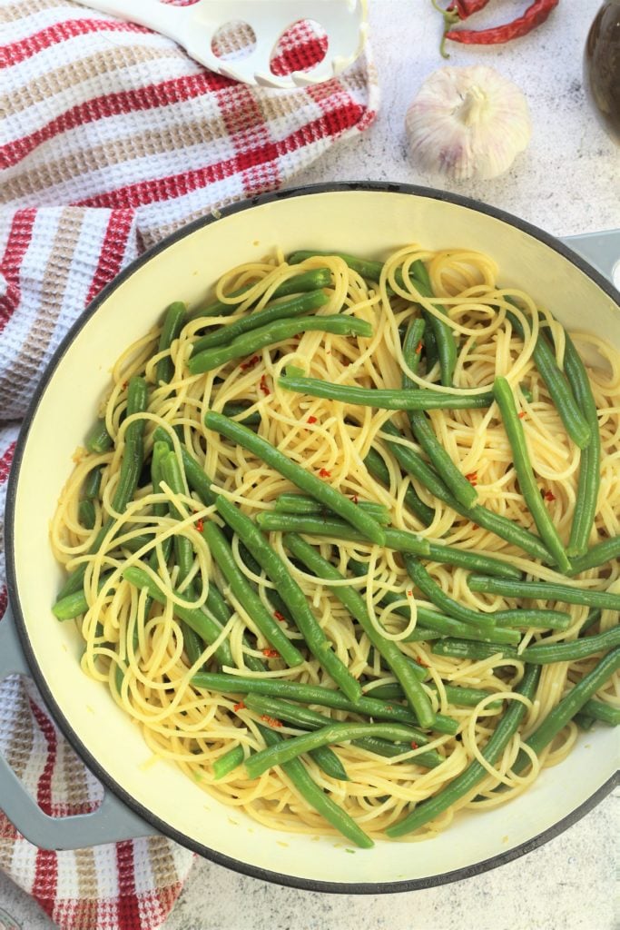 large skillet filled with green beans and spaghetti tossed with garlic and red chili flakes