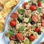 oval platter filled with tuna and white bean salad with crostini, a lemon and olive oil on the side