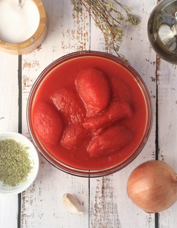 bowl of whole peeled tomatoes, onion, garlic bowl of oregano, salt and olive oil