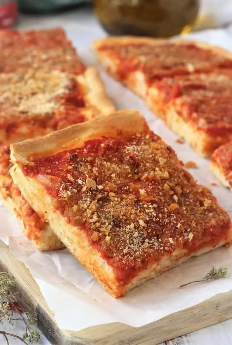 squares of tomato topped pizza overlapped on wood board 