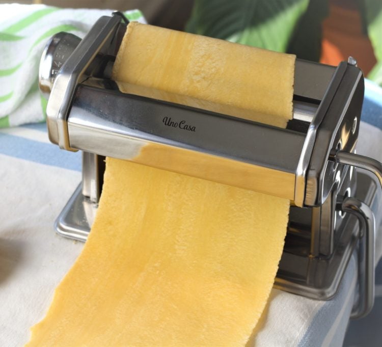 pasta maker with sheet of pasta dough through the rollers 