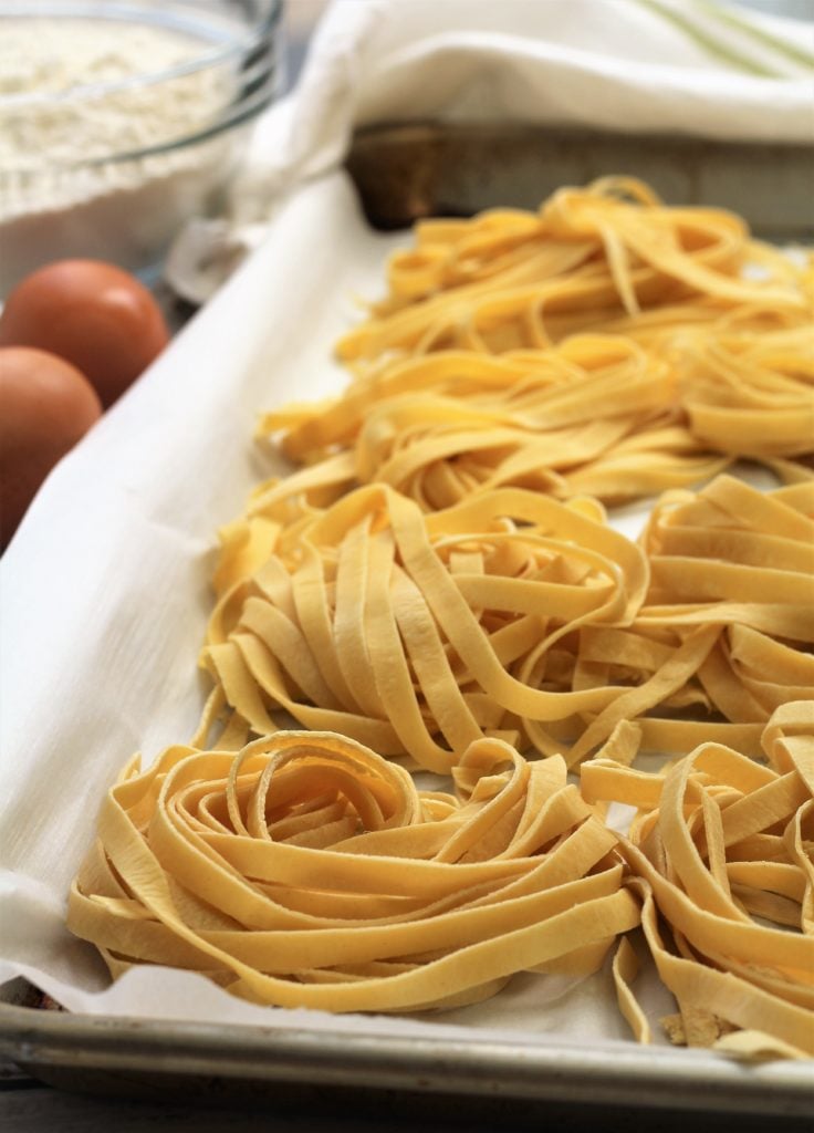 nests of fresh tagliatelle pasta on baking sheet 