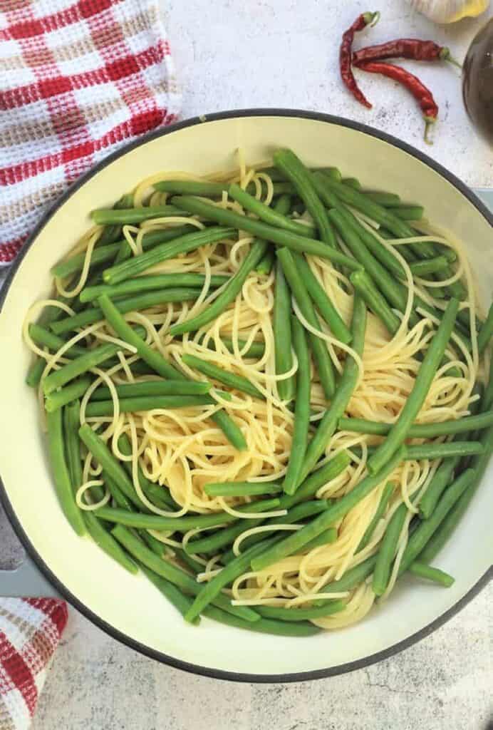 Spaghetti with green beans tossed in large skillet.