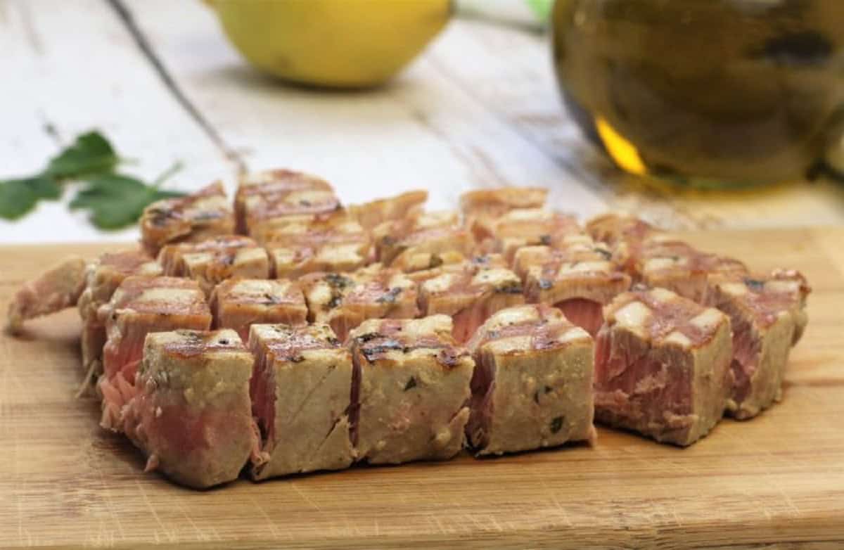 Diced grilled tuna steak on wood board.