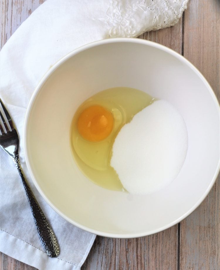whole egg and sugar in bowl with fork on side