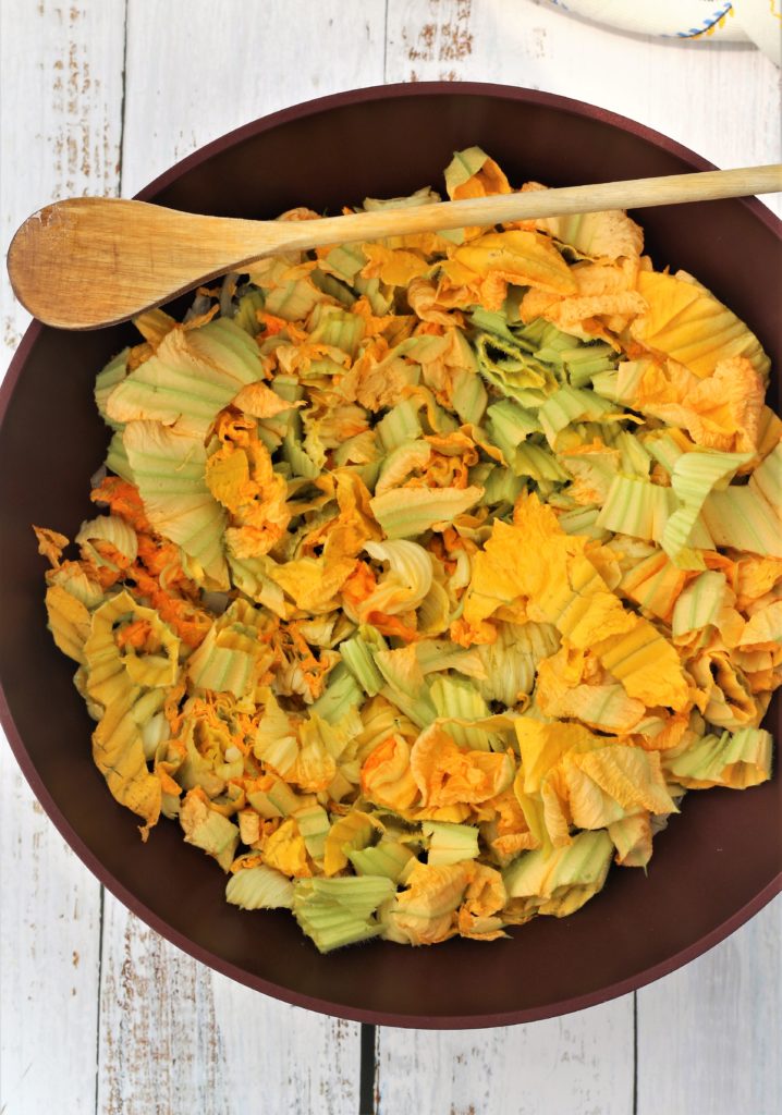 large red skillet with chopped zucchini blossoms