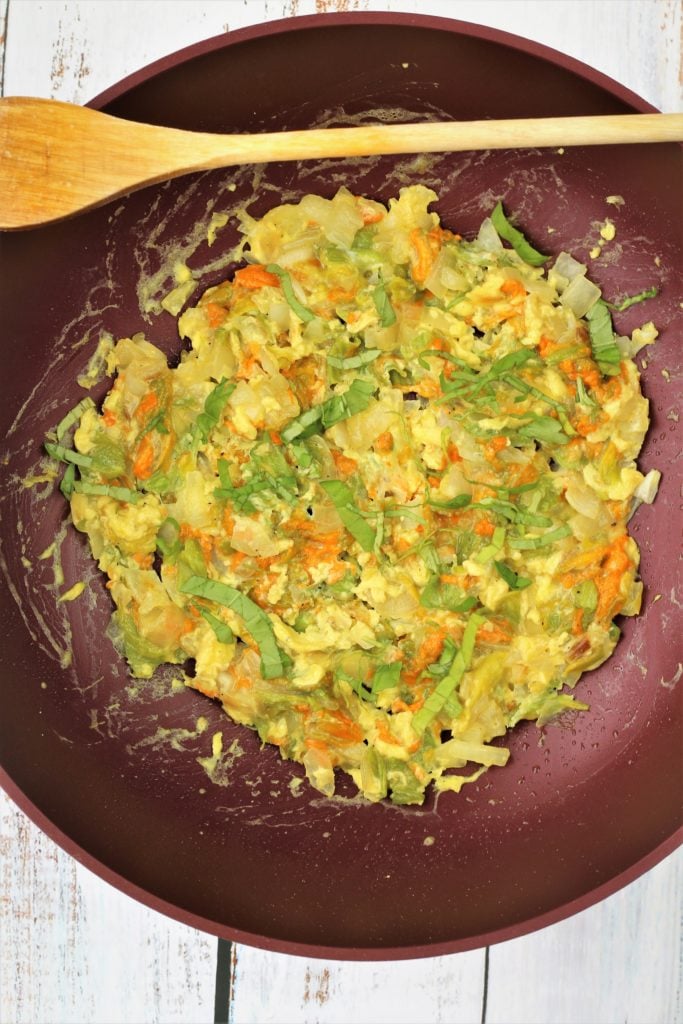 zucchini blossom and egg scramble in large red skillet 