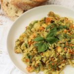 white plate with scrambled eggs with zucchini blossoms and sliced bread