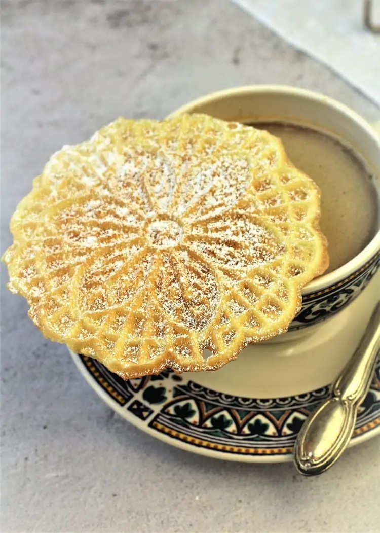 pizzelle cookie on coffee cup filled with coffee on saucer