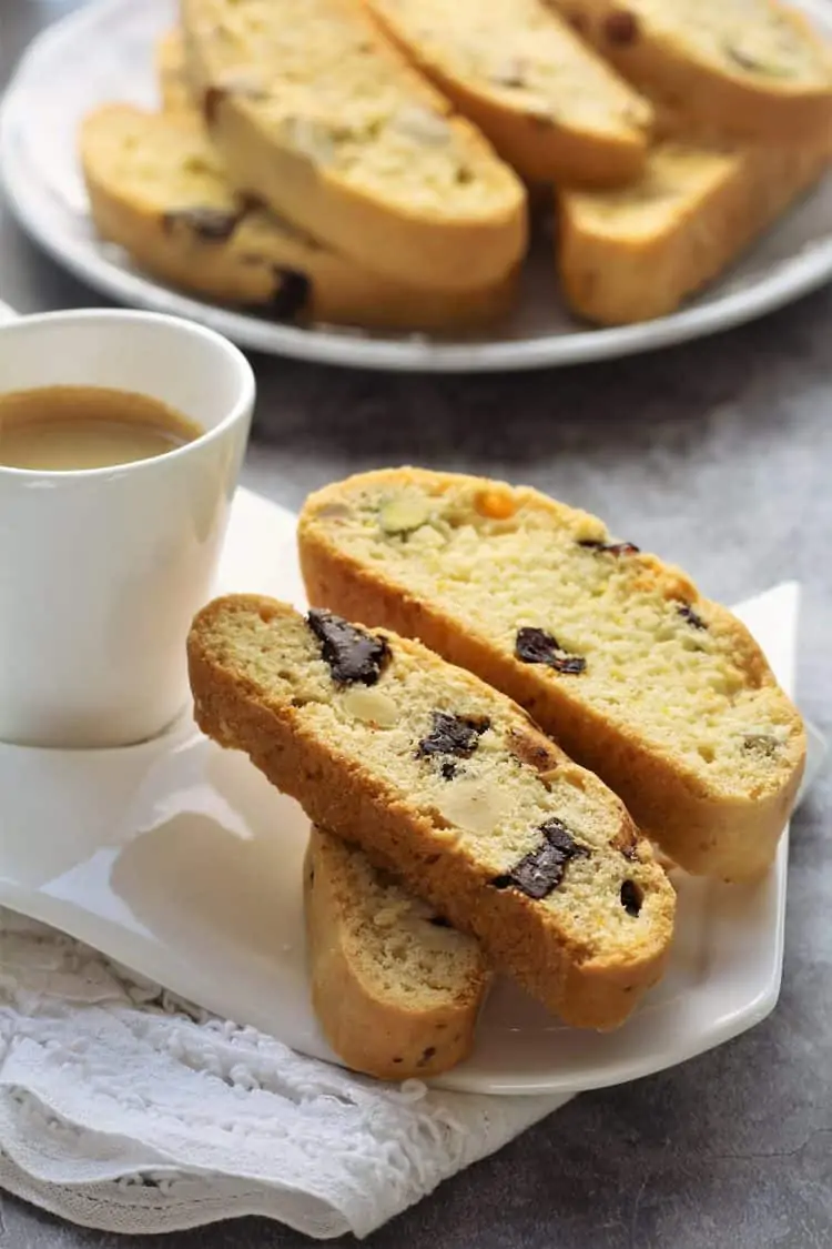 cup of espresso in white cup with biscotti on side and plated in background