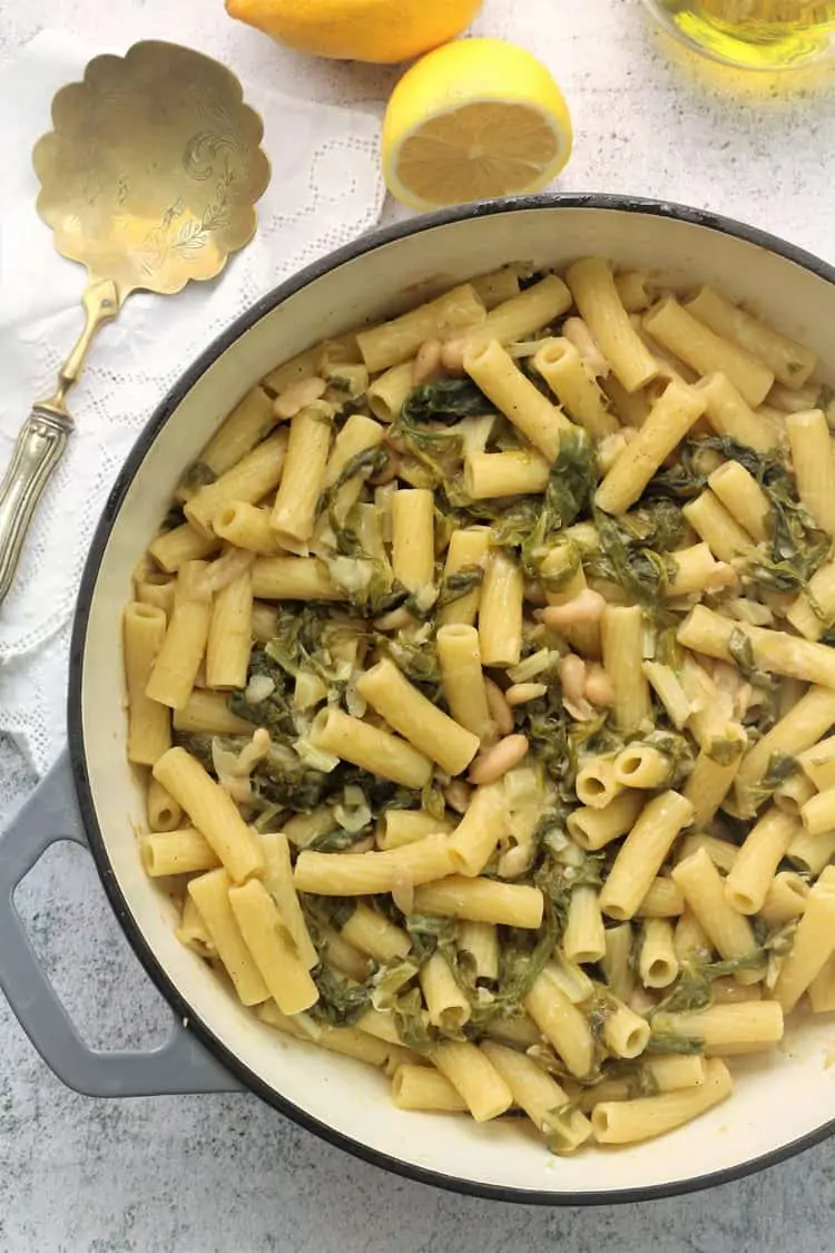 large grey skillet filled with pasta with swiss chard and white beans
