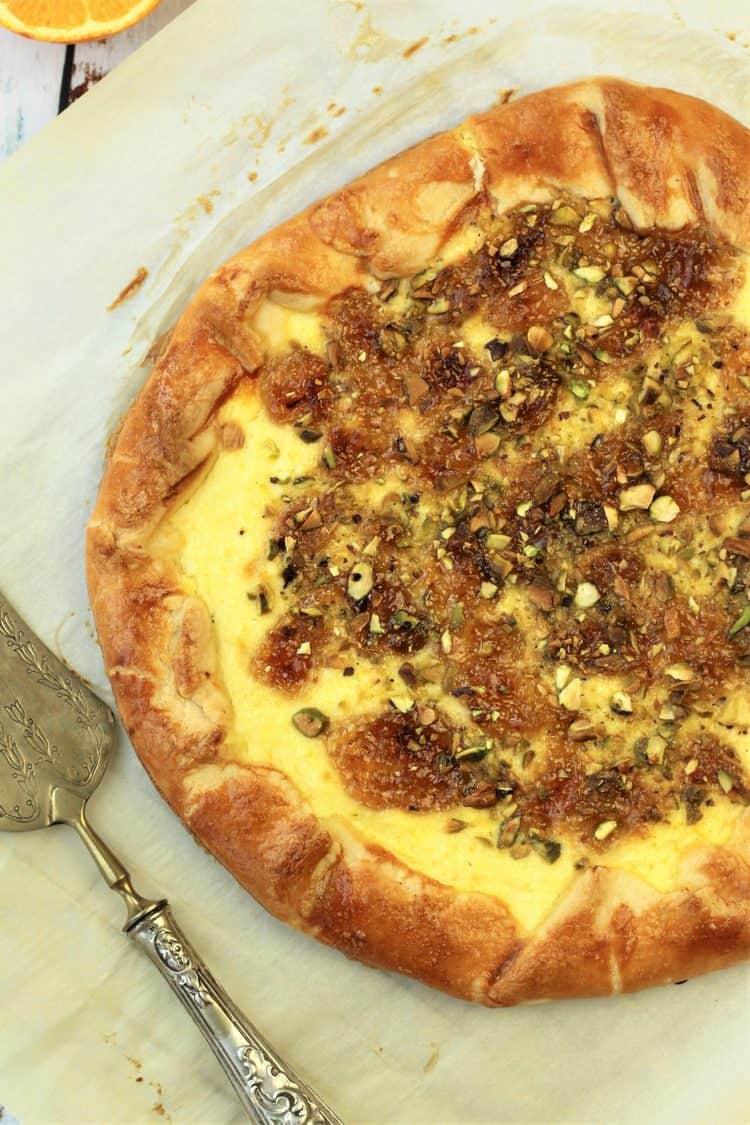 crostata pie topped with fig jam, ricotta and pistachios on parchment paper