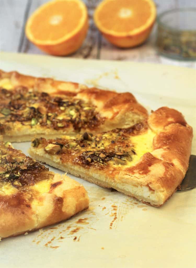 wedge of crostata on spatula with orange wedges in background