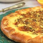 crostata topped with fig jam, ricotta and pistachios on green serving platter