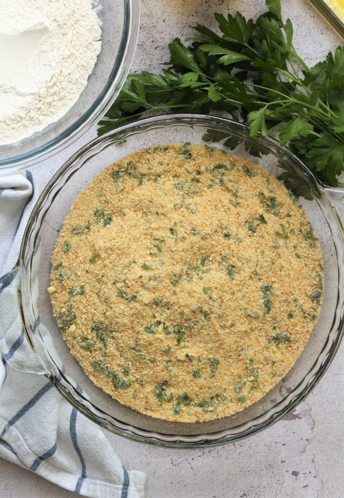 bowl of seasoned breadcrumbs surrounded by parsley and bowl of flour