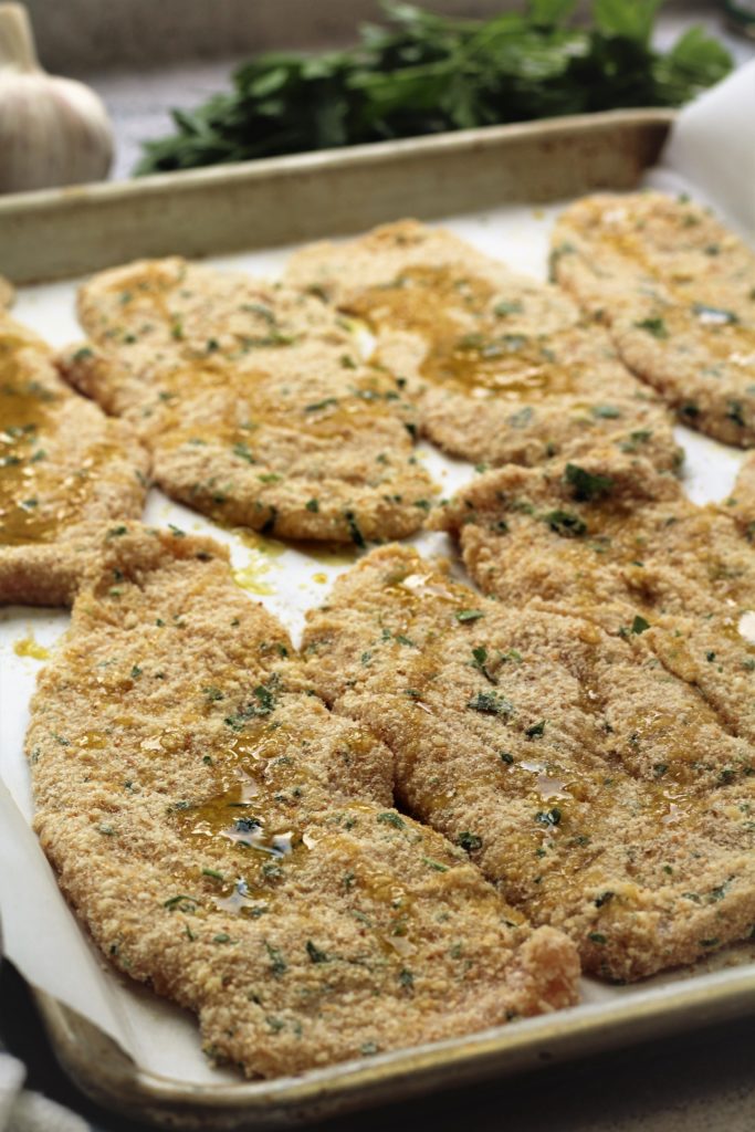 chicken cutlets on baking sheet drizzled with olive oil